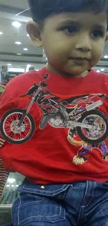 Adorable young boy wearing red shirt with motorcycle design.