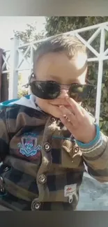 Adorable child with sunglasses in a checkered jacket.