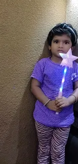 Child holding a glowing wand with purple attire against a textured wall.