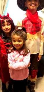 Three kids in Halloween costumes with smiles.