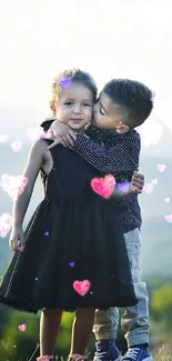 Two children hugging on a green hillside with mountains in the background.