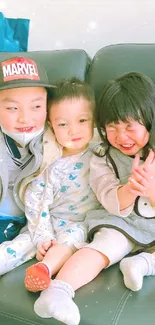 Three happy children sitting together on a couch, smiling warmly.