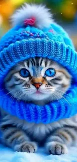 Adorable blue-eyed kitten in hat and scarf against snowy backdrop.