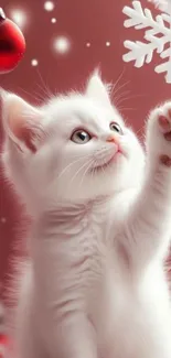 White kitten reaching for a snowflake with a red background.