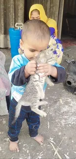 Child holding a kitten in a rustic setting, showcasing love and innocence.