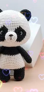 Cute panda knit toy with colorful hearts on a mobile wallpaper.