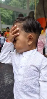 Child in white traditional outfit with a thoughtful pose.