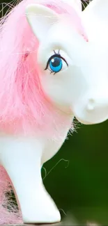 Cute toy horse with pink mane and vivid eyes on a green background.