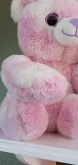 Pink fluffy teddy bear sitting on a shelf, perfect for a cute mobile wallpaper.