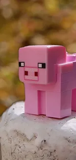 Pink pixelated pig toy on a blurred autumn background.