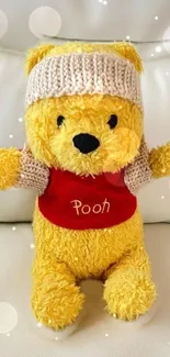 Adorable yellow plush bear wearing a hat and red shirt on a cozy background.