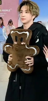 Person holding a gingerbread plush in cozy winter attire.