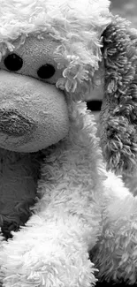 Black and white plush puppy toy sitting on wooden background.