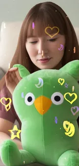 Cute green plush toy with heart shapes on a mobile wallpaper.