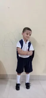 Young school kid in cute pose against a beige wall background.