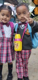 Two smiling school kids posing with peace signs and a butterfly in the background.