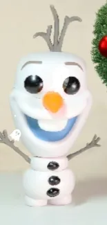 Smiling snowman figurine beside a Christmas ornament.