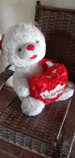 White teddy bear with red heart sitting on a chair.