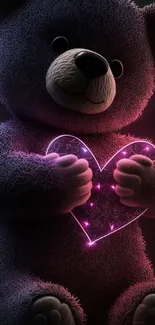 Teddy bear holding a glowing pink heart in the dark.