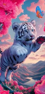 Cute white tiger cub reaches for colorful butterfly among pink blooms.