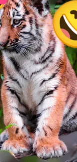 Cute tiger cub sitting among leaves with playful emojis.