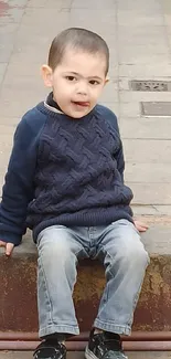 Toddler in blue sweater sitting on steps.