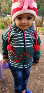 Child in striped winter jacket and hat at park.