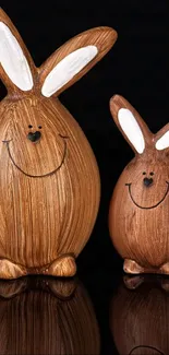 Two smiling wooden bunny figurines on a dark background.