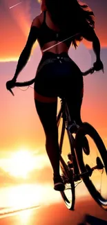 Cyclist silhouette against orange sunset sky.