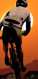 Silhouette of a cyclist at sunset with an orange sky backdrop.