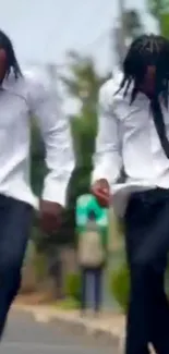 Two people dancing energetically on the street in stylish attire.