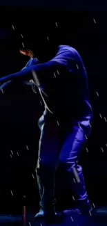 Dancer performing under blue neon lights at night.