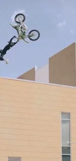 Motorcycle performing a high-flying stunt over a beige urban building.