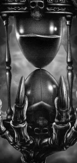 Gothic hourglass with skull and skeletal hand in monochrome.