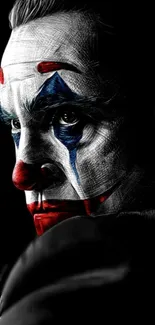 Dark wallpaper featuring Joker clown face with red, blue, and white details.