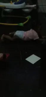 Baby crawling in a dimly lit room, surrounded by toys.