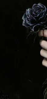 Dark hand holding a blue rose on a black background.