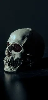 Dark shadowy skull on black background in dramatic lighting.