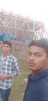 Two friends at an amusement park with colorful rides.