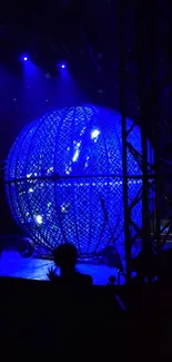 A dazzling blue-lit circus globe with a performer silhouette.