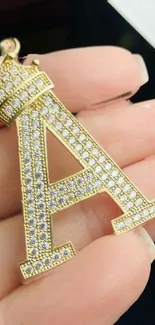 Gold letter A pendant with diamonds on a hand showcasing luxury.