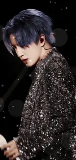 Performer with blue hair in sparkling black on stage.