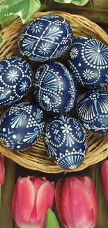 Beautifully decorated Easter eggs in a basket with tulips and greenery.