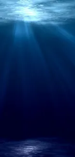 Deep blue ocean wallpaper with glowing light rays underwater.