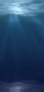 Serene underwater scene with light rays illuminating deep blue ocean water.