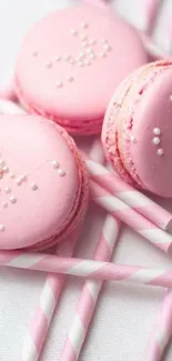 Pink macarons with white pearls on striped straws wallpaper.