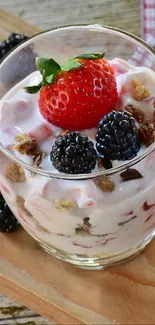 A glass of berry yogurt with strawberries and blackberries.