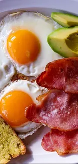 Appetizing breakfast plate with eggs, bacon, avocado, and toast on a wooden table.