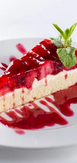 Vibrant cheesecake with red berry sauce and mint on a white plate.