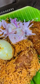 Chicken biryani on a banana leaf with sides.